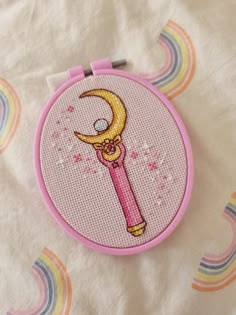 a cross stitch pattern with a pink needle and a yellow moon on it's side