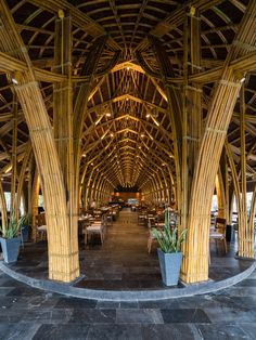 the inside of a bamboo building with tables and chairs in it's center area