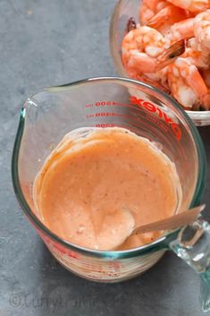 a glass bowl filled with sauce next to another bowl full of shrimp and carrots