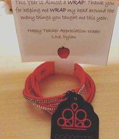 a red bracelet with an apple on it and a thank note attached to the wrist