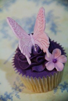 a cupcake with purple frosting and pink butterflies on top