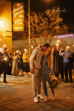 a man and woman kissing in front of people holding sparklers