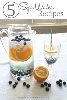 a pitcher filled with water next to an orange slice and some blackberries on a table