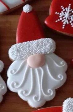 decorated cookies with santa hats and snowflakes are on a wooden table next to candy canes