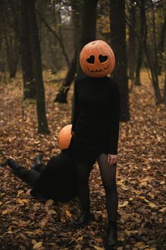 a woman in a black dress with a pumpkin hat on her head and a dog laying on the ground