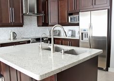 a kitchen with marble counter tops and stainless steel appliances in the center, along with dark wood cabinets