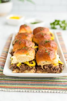 three sandwiches with cheese and meat on a white plate sitting on a colorful place mat