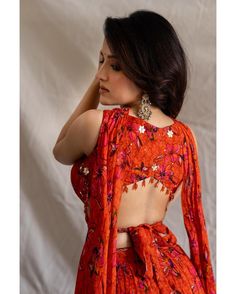 a woman in an orange floral print dress with her back to the camera, looking off into the distance