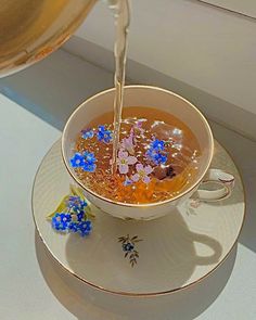 a tea cup filled with liquid being poured into it