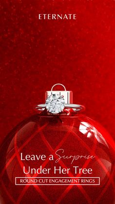 a red christmas ornament with a diamond ring on it and the words leave a surprise under her tree round cut engagement rings