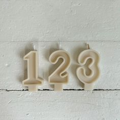 the number twenty two and three candles are arranged in front of a white brick wall