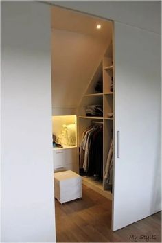 an open closet with clothes on hangers and a white stool in the corner next to it