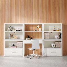 a white chair sitting in front of a book shelf filled with books and other items