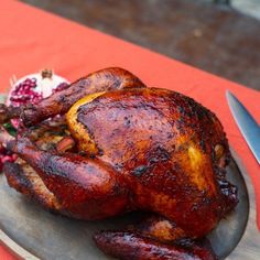 a roasted turkey sits on a plate next to a knife