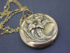 Stunning antique locket that features a raised floral design with a rhinestone, very beautiful.  Opens and closes with a snap.  Has some age related wear and patina.  No frames/covers inside unfortunately.   Marked WH&CO inside.  Comes with a brand new 18" gold-plated stainless steel chain. Visit Ribbons Edge for more great pieces of vintage and antique jewelry!  All items added to your cart at Ribbons Edge will automatically combine shipping. To stay up to date with my newest offerings, follow me on IG @ RibbonsEdge Victorian Round Necklace With Antique Finish, Heirloom Antique Gold Locket Necklace With Antique Finish, Heirloom Antique Gold Locket Necklace, Elegant Medallion Locket Necklace With Antique Finish, Heirloom Antique Finish Necklace For Weddings, Elegant Patina Jewelry For Weddings, Heirloom Wedding Necklace With Antique Finish, Heirloom Antique Finish Wedding Necklace, Antique Engraved Locket Necklace With Flower Pendant