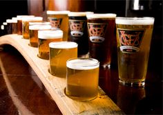 a wooden table topped with lots of glasses filled with beer