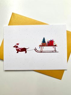 a card with a dachshund pulling a sleigh