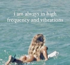 a woman in the ocean on her surfboard with an inspirational quote above it that reads, i am always in high frequency and vibrations