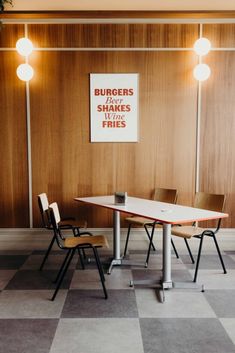 a table and chairs in a room with wood paneling on the wall behind them