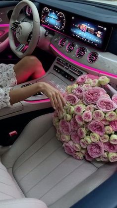 a woman sitting in the driver's seat of a car holding a bouquet of roses