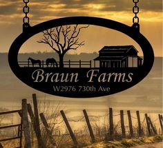 the sign for braun farms is hanging from a chain with horses in the pasture behind it