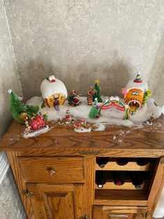 a wooden cabinet topped with lots of snow covered christmas decorations and figurines on top of it