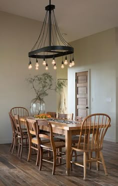 a dining room table with chairs and a chandelier hanging from it's ceiling