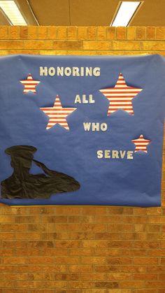 a sign that says honoring all who serve hangs on a brick wall in a school hallway