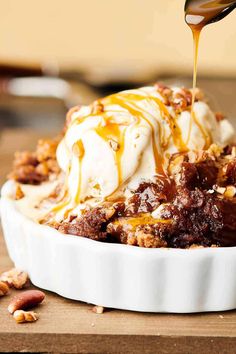 a spoon drizzling caramel sauce onto a dessert in a white dish