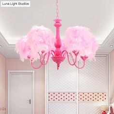 a pink chandelier hanging from the ceiling in a room with white walls and flooring