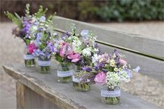 flowers in mason jars lined up on a bench