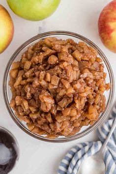 a bowl filled with granola next to apples