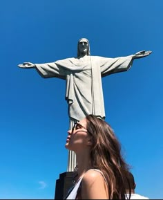 a woman looking up at the statue of christ