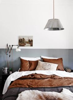 a bed with brown and white sheets in a bedroom next to a painting on the wall