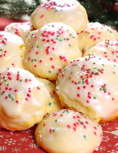 christmas cookies with white frosting and sprinkles on a red tablecloth