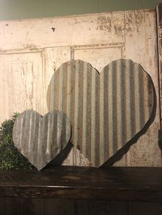 two heart shaped metal pieces sitting on top of a wooden shelf next to each other