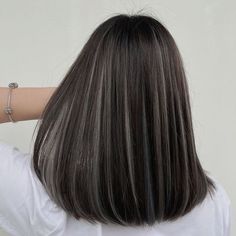 the back of a woman's head with long dark hair and silver bracelets