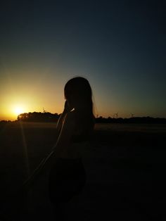 the silhouette of a woman talking on her cell phone in front of an orange and blue sunset