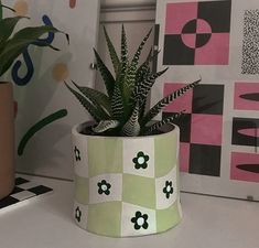 a potted plant sitting on top of a white table next to a pink and black checkered wall