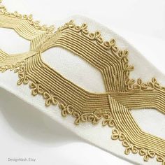 a white and gold mask on a white table cloth with golden threadwork around the edges