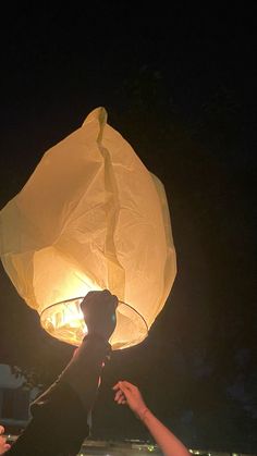 a person holding up a paper lantern in the air