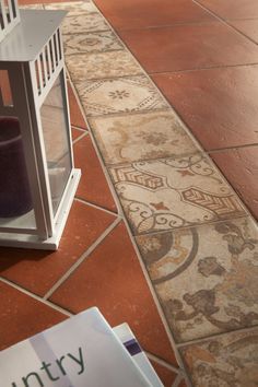 a small white lantern sitting on top of a tiled floor next to a magazine rack