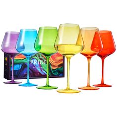 four different colored wine glasses sitting next to each other in front of a black box