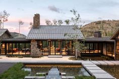 the house is surrounded by mountains and has a pond in front of it, as well as an outdoor seating area