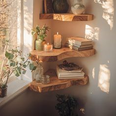 three wooden shelves with books and candles on them in front of a window sill