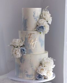 a three tiered wedding cake with blue and white flowers