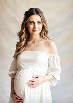 a pregnant woman wearing a white dress and holding her belly in front of the camera