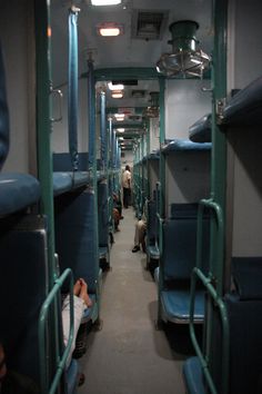 the inside of a train car with blue seats and people sitting on it's sides