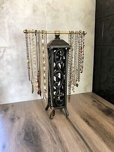 an ornate metal candle holder with beads and chains hanging from it's sides on a wooden table