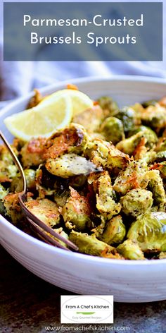 a white bowl filled with brussel sprouts and lemon wedges